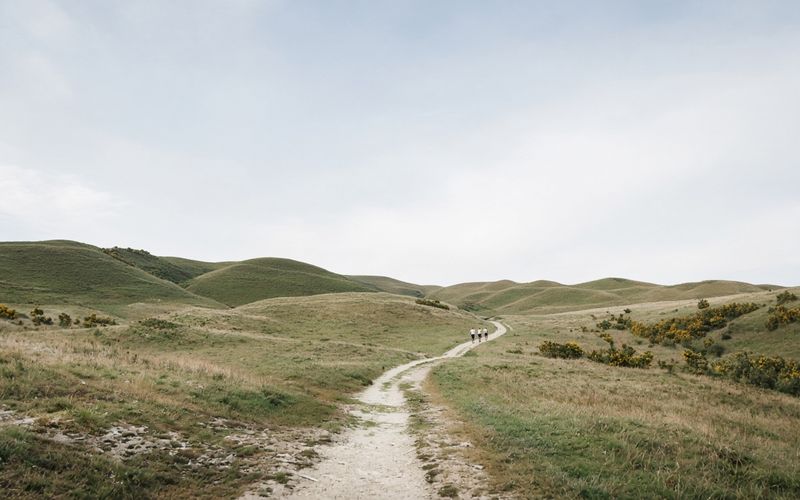 Three runners far along a path on open downs