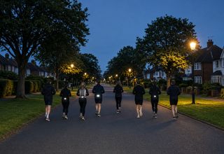 A small group running down a tree-lined street at dusk